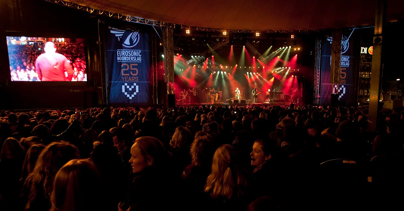 Crowd in front of a lit stage with Eurosonic Noorderslag banners during the 25th-anniversary festival in Groningen