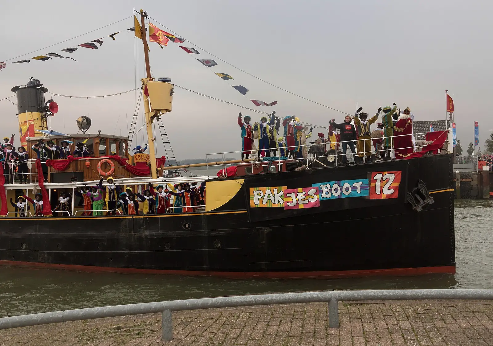 The Pakjesboot steamer carrying Sinterklaas and helpers arrives at the quay with onlookers waving, at the 2016 national arrival in Maassluis